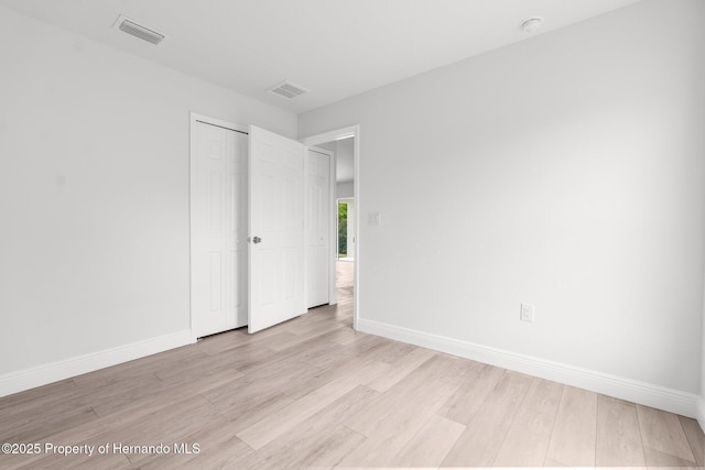 unfurnished room featuring light wood-type flooring, visible vents, and baseboards