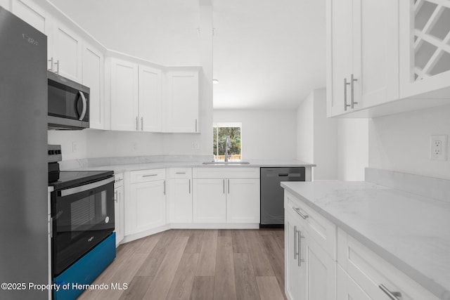 kitchen with light stone countertops, stainless steel appliances, light wood-type flooring, white cabinetry, and a sink