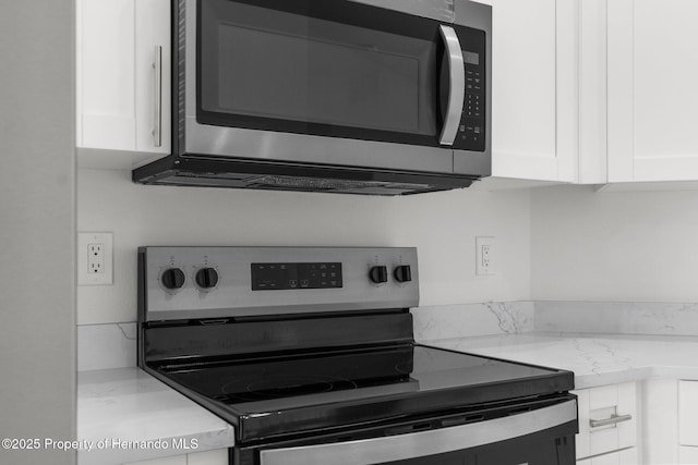 kitchen featuring light stone countertops, white cabinetry, and stainless steel appliances