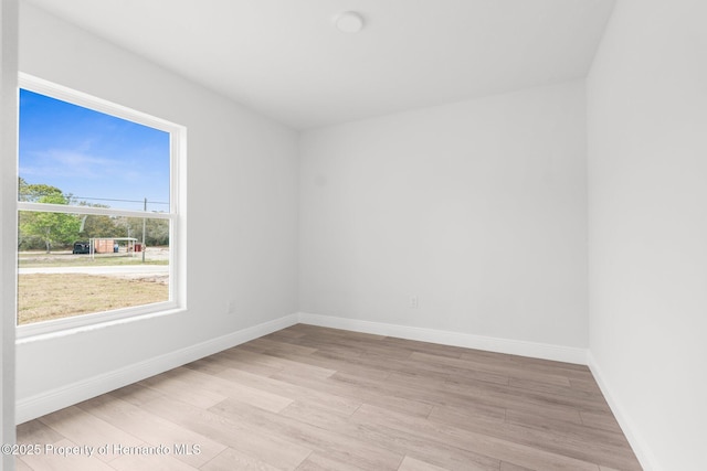 unfurnished room with light wood-type flooring and baseboards