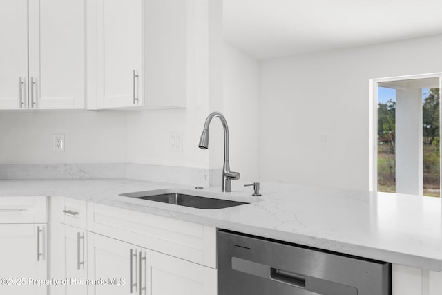 kitchen with light stone counters, white cabinetry, a sink, and dishwasher