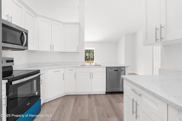 kitchen with light wood-style flooring, white cabinetry, stainless steel appliances, and a sink