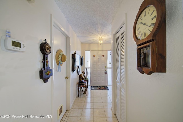 corridor with light tile patterned floors and a textured ceiling