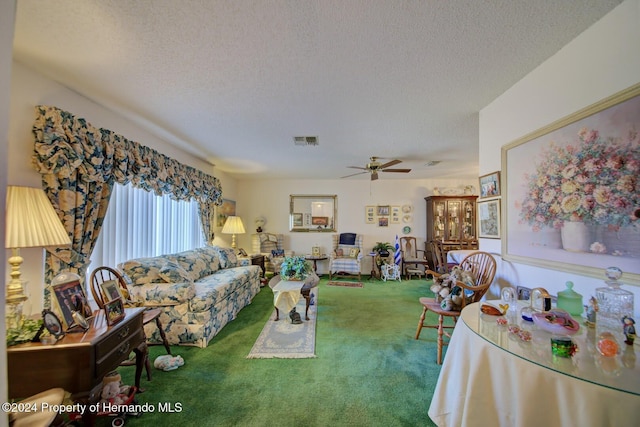 living room with ceiling fan, carpet floors, and a textured ceiling