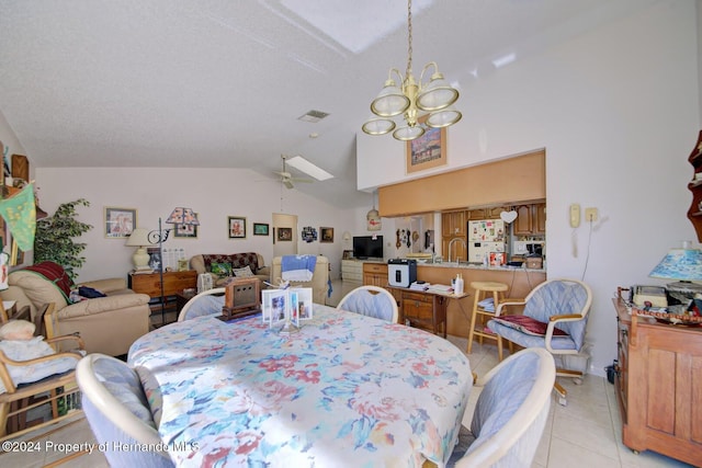 tiled dining room featuring a textured ceiling, lofted ceiling, sink, and ceiling fan with notable chandelier