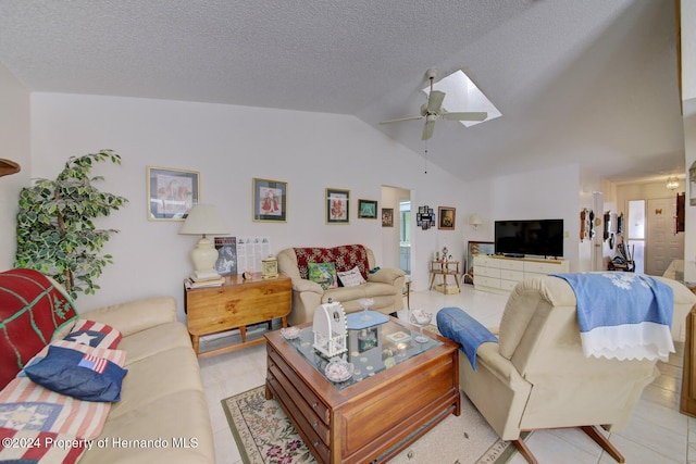 living room featuring light tile patterned floors, lofted ceiling with skylight, and ceiling fan