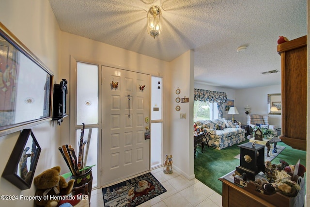 foyer entrance featuring light tile patterned floors and a textured ceiling