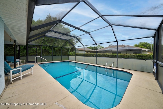 view of pool with glass enclosure and a patio