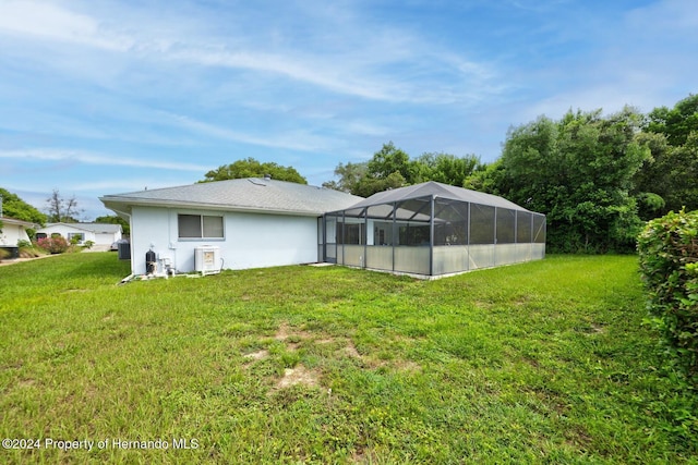 rear view of house with a lanai and a lawn