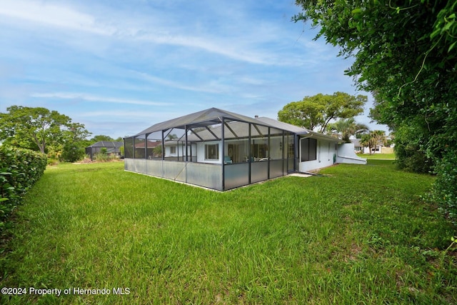 rear view of property with a lawn and a lanai