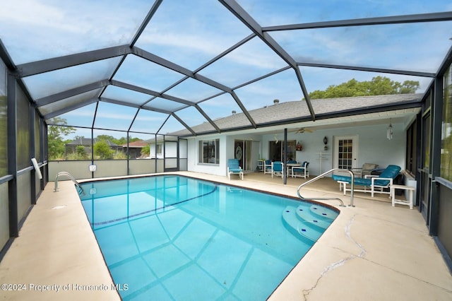 view of pool with glass enclosure, a patio area, and ceiling fan