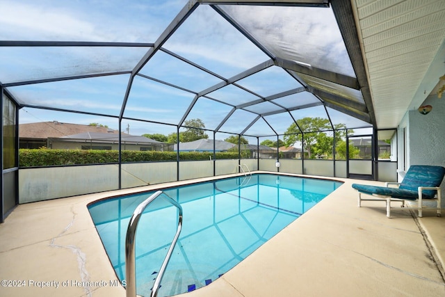 view of pool with glass enclosure and a patio