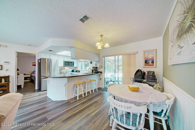 dining space featuring sink, dark hardwood / wood-style flooring, a textured ceiling, and a chandelier