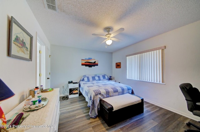 bedroom with a textured ceiling, ceiling fan, and dark wood-type flooring