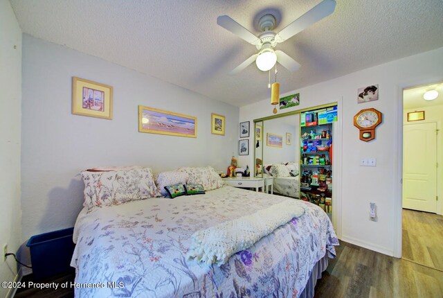 bedroom featuring ceiling fan, a closet, wood-type flooring, and a textured ceiling