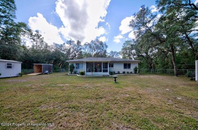 back of property with a lawn and a storage shed