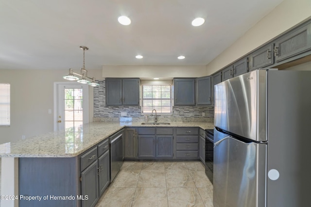 kitchen with kitchen peninsula, a healthy amount of sunlight, stainless steel appliances, and decorative light fixtures