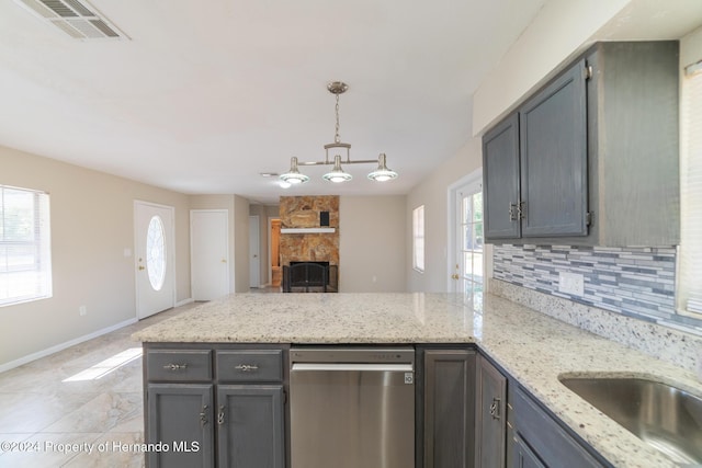 kitchen featuring light stone countertops, tasteful backsplash, decorative light fixtures, a fireplace, and gray cabinets