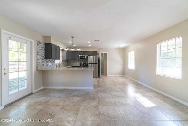 kitchen with plenty of natural light, kitchen peninsula, stainless steel appliances, and tasteful backsplash