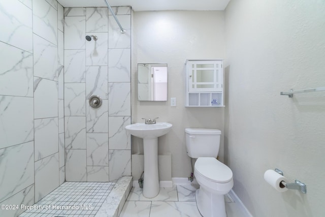 bathroom featuring sink, toilet, and tiled shower