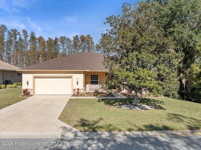 view of front of home featuring cooling unit, a garage, and a front lawn