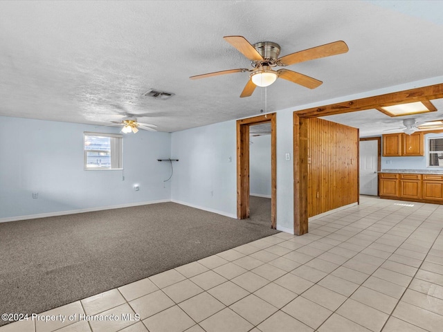 unfurnished living room with light carpet, ceiling fan, and a textured ceiling