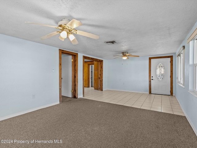 interior space with ceiling fan, light colored carpet, and a textured ceiling