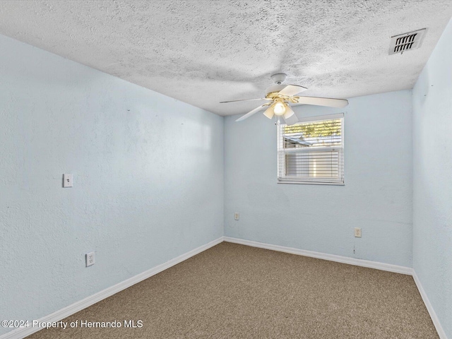 carpeted empty room with ceiling fan and a textured ceiling