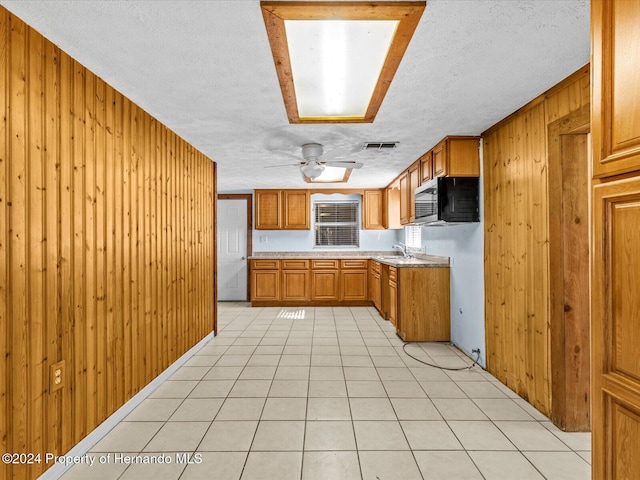 kitchen featuring wooden walls, light tile patterned floors, and a textured ceiling