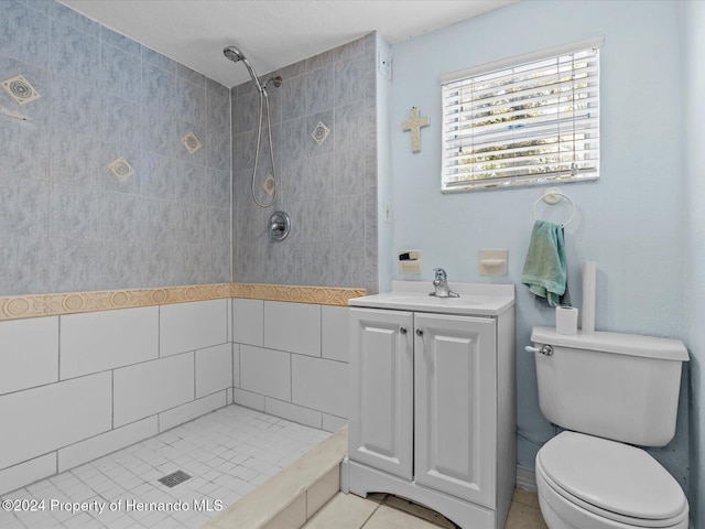 bathroom with tile patterned floors, vanity, toilet, and tiled shower