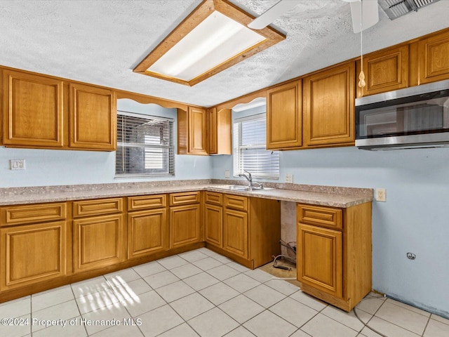 kitchen with light tile patterned floors, a textured ceiling, and sink