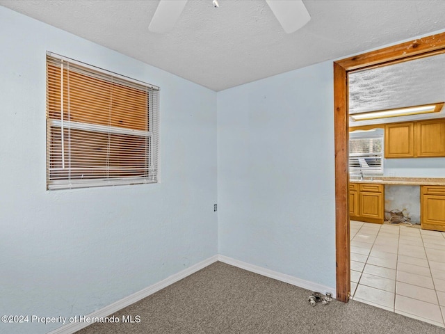 carpeted empty room with ceiling fan and a textured ceiling