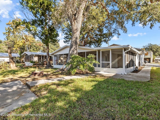 rear view of property featuring a sunroom and a lawn