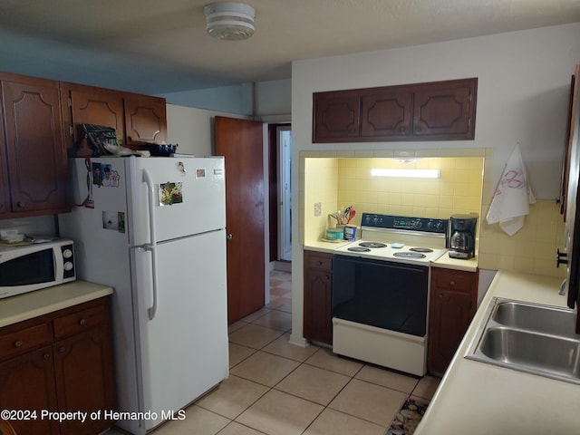 kitchen featuring tasteful backsplash, sink, light tile patterned flooring, and white appliances