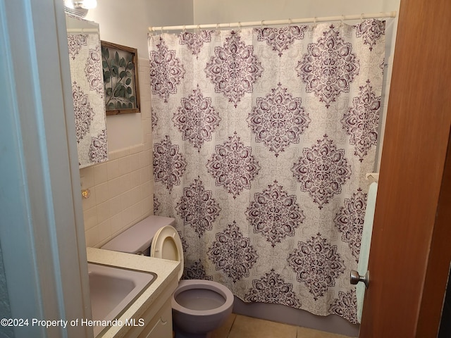 bathroom with tile patterned floors, vanity, toilet, and tile walls