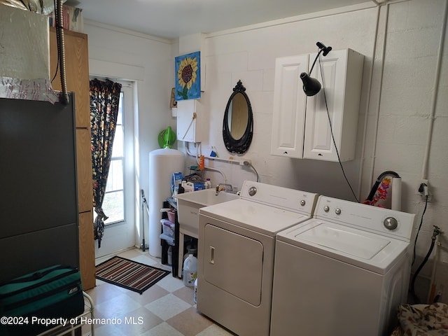 washroom with cabinets, washer and clothes dryer, and sink