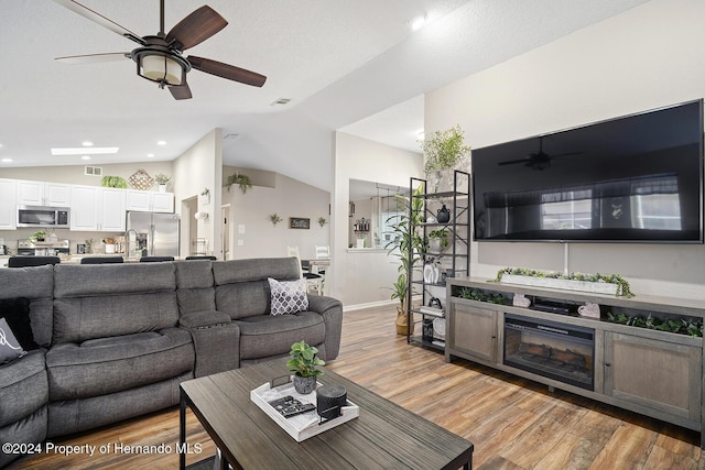 living room featuring light wood-type flooring and vaulted ceiling