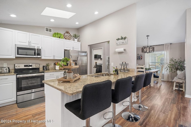 kitchen with a center island with sink, white cabinets, a skylight, dark hardwood / wood-style floors, and stainless steel appliances