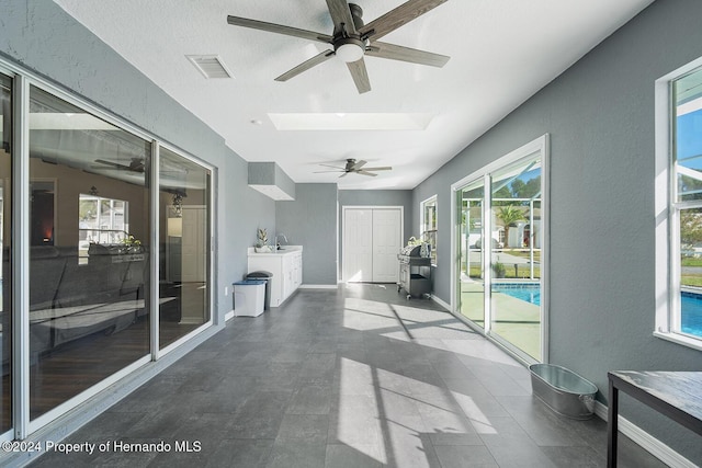 sunroom / solarium featuring lofted ceiling with skylight, sink, and ceiling fan