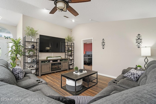 living room with a textured ceiling, dark hardwood / wood-style flooring, vaulted ceiling, and ceiling fan