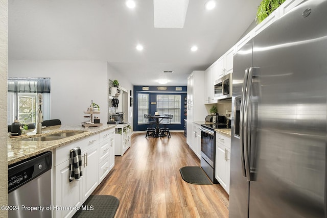 kitchen with light stone countertops, sink, light hardwood / wood-style flooring, white cabinets, and appliances with stainless steel finishes