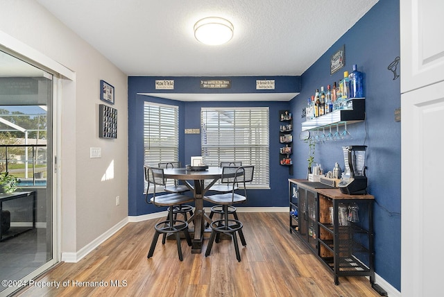 dining area with bar, hardwood / wood-style flooring, and a wealth of natural light