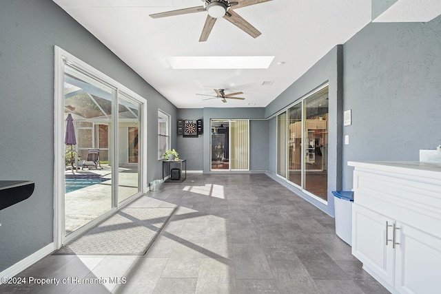 unfurnished sunroom featuring ceiling fan and a skylight