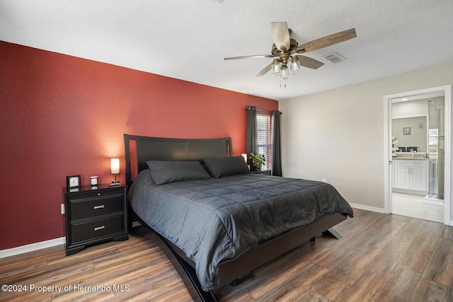 bedroom with connected bathroom, ceiling fan, hardwood / wood-style floors, and a textured ceiling