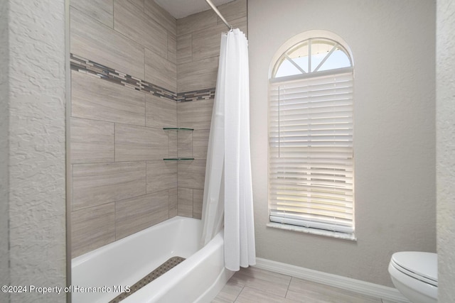 bathroom featuring toilet and shower / bathtub combination with curtain