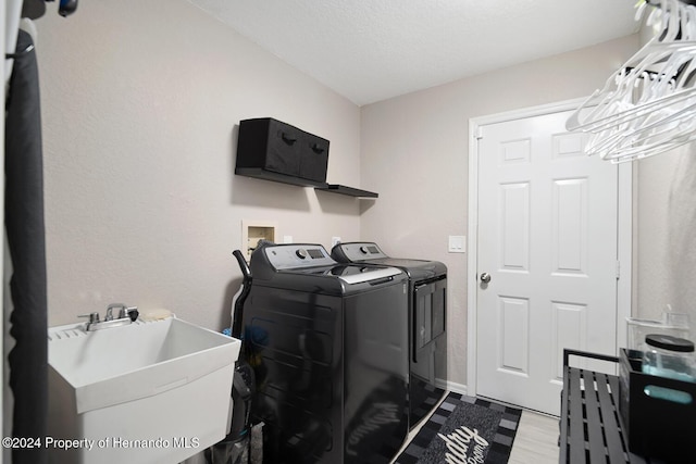 laundry room featuring a textured ceiling, sink, and washing machine and clothes dryer