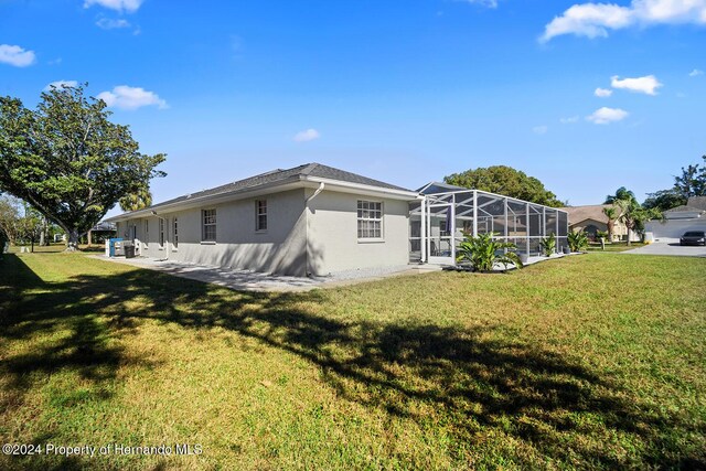 back of house with a lanai and a lawn