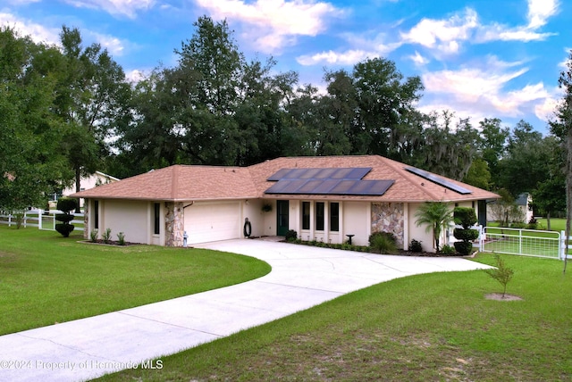 ranch-style house featuring solar panels, a garage, and a front lawn