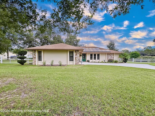 ranch-style home with a front yard and solar panels