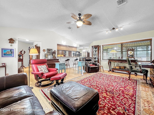 living room featuring a textured ceiling, ceiling fan, wood-type flooring, and lofted ceiling